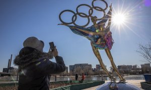 Una mujer fotografía una escultura de una pareja de patinaje artístico con motivo de los Juegos Olímpicos de Invierno 2022 en el parque industrial Shougang en Pekín.