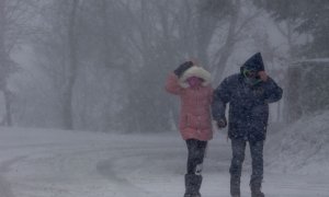 Un hombre y una mujer se protegen del temporal, a 27 de noviembre de 2021, en Pedrafita do Cebreiro, Lugo, Galicia.