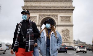 Los peatones con mascarillas caminan por los Campos Elíseos en el centro de París.