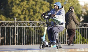 Una persona en su patinete, en Puente de Triana, en Sevilla.