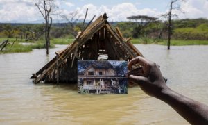 Un hombre sujeta una fotografía que muestra cómo era su hogar en Kenia antes de una inundación.