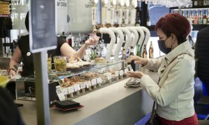 07/03/2022-Una mujer paga su consumición en el interior de un bar