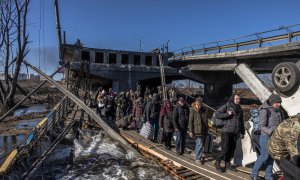 Ciudadanos de Irpin cruzan un puente destruido mientras huyen de la ciudad.