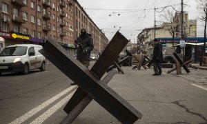 Un voluntario de las Fuerzas de Defensa Territorial de Ucrania controla el tráfico en un puesto de control en Kiev este domingo.