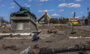 Un rescatista ucraniano examina un objeto explosivo junto a partes de vehículos militares rusos destruidos en el suelo frente a la estación de tren donde estaban estacionadas las fuerzas rusas, en la ciudad de Trostyanets, recapturada por el ejército ucra