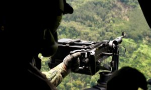 Un soldado permanece en posición en un helicóptero que sobrevuela la zona donde fuerzas militares -en la víspera- capturaron al narcotraficante Dairo Antonio Úsuga, alias Otoniel, cerca de Carepa, departamento de Antioquia, Colombia, el 24 de octubre de 2