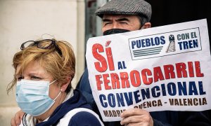 Dos personas sostienen una pancarta que reza 'Pueblos con el tren, Sí al ferrocarril convencional', en una manifestación de Aranjuez por el mantenimiento de la línea Valencia-Cuenca-Madrid.