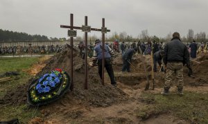 Varias personas entierran un cuerpo en el cementerio de Bucha (Ucrania) el 22 de abril de 2022.