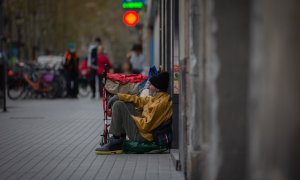 Una persona sin techo permanece en el suelo de una calle cercana al Hospital de campaña instalado en la parroquia de Santa Anna, en Barcelona, Catalunya, (España), a 14 de noviembre de 2020.