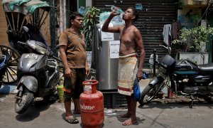 Un hombre bebe agua de una botella que sacó de una nevera instalada por un residente local junto a una carretera para distribuir agua fría gratis a los transeúntes, durante el clima cálido en Calcuta, India , el 26 de abril de 2022.