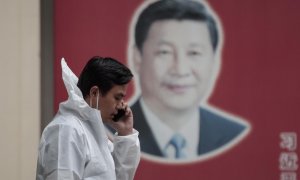 Un hombre con equipo de protección habla por teléfono en la calle, frente al cartel del presidente chino Xi Jinping, en medio del bloqueo de Covid-19 en Shanghái, China, el 23 de mayo de 2022.