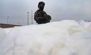 Un policía antidrogas hace guardia junto a la cocaína incautada en una instalación aduanera en el puerto de Callao, Perú, el 11 de junio de 2022.