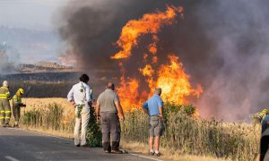 Varios vecinos observan las llamas del incendio declarado este domingo por la tarde en el término municipal de Quintanilla del Coco, en Burgos.