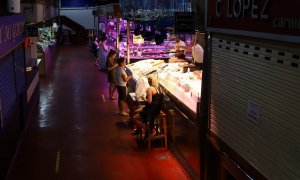 Varias personas esperan su turno para hacer la compra en el Mercado de la Cebada, en Madrid.