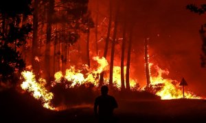 11/08/2022-Una silueta se ve delante de las llamas en un incendio forestal cerca de Belin-Beliet, suroeste de Francia, durante la noche del 11 de agosto de 2022. Las autoridades francesas han advertido de que las llamas podrían provocar un gran incendio f