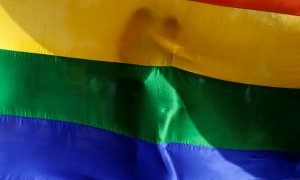 Dos personas se abrazan mutuamente tras una bandera arcoiris durante una vigilia en memoria de las víctimas del tiroteo del club gay Pulse de Orlando en Bombay, India