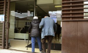 Dos personas mayores entran por la puerta de la residencia.