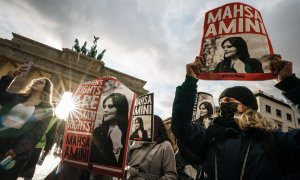 28/09/2022-Manifestantes sostienen pancartas con una imagen de Mahsa Amini durante una concentración en reacción a su muerte, frente a la Puerta de Brandenburgo en Berlín, Alemania, 28 de septiembre de 2022.