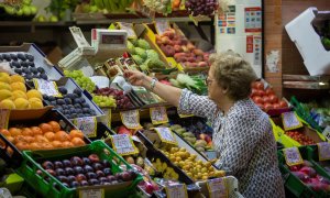 Una mujer compra en uno de los puestos del mercado de abastos de Triana. A 13 de septiembre de 2022, en Sevilla.