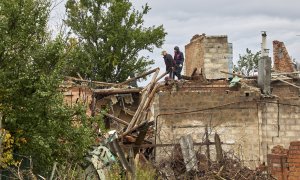 Ciudadanos limpian los escombros de un edificio dañado por los bombardeos en la aldea de Ruski Tyshky del área de Kharkiv.