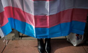 Los zapatos de una mujer debajo de una bandera trans durante una concentración de la Federación Plataforma Trans, en la sede del PSOE en la calle Ferraz, a 28 de octubre de 2022, en Madrid.