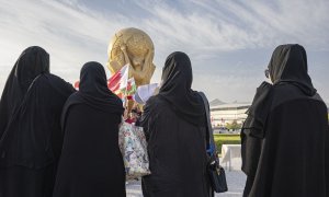 Mujeres en Catar con una recreación gigante de la Copa del Mundo al fondo.