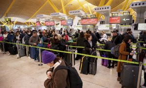 viajeros hacen cola ante los mostradores de 'check-in' de las compañías aéreas este viernes en el aeropuerto de Madrid Barajas.