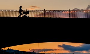 Una madre con un carrito de bebe paseando al atardecer por el Puente de Triana en Sevilla el 28 de abril del 2020.