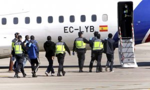 Agentes de policía embarcan a varias personas migrantes en un vuelo de deportación, en una imagen de archivo.