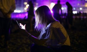 Imagen de archivo de una mujer mientras utiliza su teléfono móvil en una fiesta, a 14 de agosto de 2022.