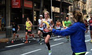 17-3-2023 Una voluntària ofereix un plàtan a una participant mentre corre a la Marató de Barcelona