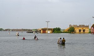 Los desplazados internos caminan a través de las inundaciones para regresar a sus hogares después de las fuertes lluvias monzónicas en Pakistán.