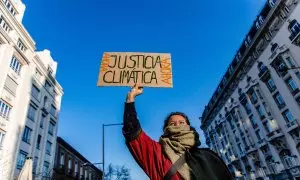 Una mujer sujeta una pancarta durante una manifestación del movimiento ‘Juventud por el Clima’, frente al Congreso de los Diputados, a 3 de marzo de 2023, en Madrid.