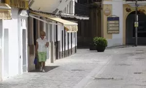 Una mujer intenta caminar por la sombra de los toldos por la calle debido a las altas temperaturas que se están registrando inusuales para el mes de abril, este viernes en Sevilla.