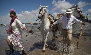 Los peregrinos cruzan el río Guadalquivir en ruta hacia el santuario de El Rocío en el parque nacional de Doñana durante la peregrinación anual de El Rocío.