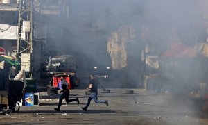 Los palestinos corren para ponerse a cubierto de los vehículos militares israelíes en medio de una redada en la ciudad ocupada de Nablus, en Cisjordania, el 14 de mayo de 2023