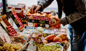 Una persona coge una caja de fresas en la frutería 'Vitaminas', a 2 de enero de 2023, en Madrid (España).