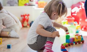 Una niña juega con el tren de madera en una escuela (Archivo)