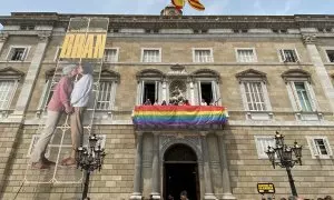 Desplegament de la lona amb la bandera LGTBI a la façana del Palau de la Generalitat.