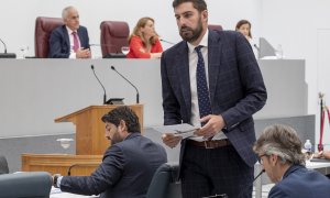 El portavoz de Vox en el Parlamento murciano José Ángel Antelo (d), pasa ante el presidente en funciones de la Comunidad de Murcia, Fernando López Miras (i), tras su intervención este viernes durante la segunda sesión del pleno de investidura del Popular