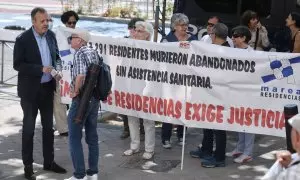 El exconsejero de Políticas Sociales Alberto Reyero (i) conversa con un hombre que participa en una concentración para pedir justicia por los residentes fallecidos durante el Covid, medios a su llegada a testificar en los Juzgados de Plaza de Castilla, a