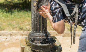 Una persona se remoja en una fuente pública de Barcelona para hacer frente al fuerte calor.