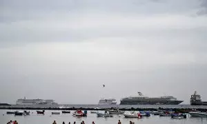 La gente disfruta de un baño mientras los cruceros están anclados en la playa de Los Cristianos, en la costa sur de la isla canaria de Tenerife, España, en el verano de 2021.