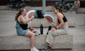 31/07/2023.- Dos jóvenes combaten el calor con sendos abanicos en este último día de julio en el País Valencià.