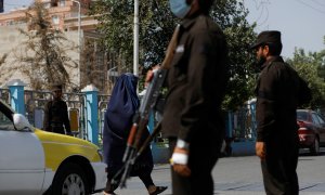 Una mujer afgana camina entre talibanes en un puesto de control en Mazar-i-Sharif, Afganistán, a 6 de agosto de 2023.