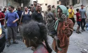 Una mujer palestina sostiene a su hijo en brazos, ambos cubiertos de polvo de los escombros tras el bombardeo israelí de un edificio residencial en la ciudad de Gaza este jueves, 12 de octubre de 2023.