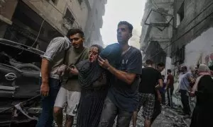 Una mujer recibe ayuda para salir de una zona bombardeada por Israel en el campo de refugiados de Al-Shati, en el oeste de la ciudad de Gaza, a 14 de octubre de 2023.