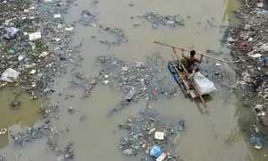 buscando productos de plástico reciclado en el canal lleno de desechos plásticos