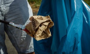 Un hombre tira un envoltorio de comida a la basura.