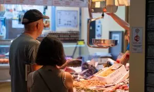 Dos personas esperando en uno de los puestos del mercado de la Encarnación, en Sevilla, a 11 de julio del 2023.